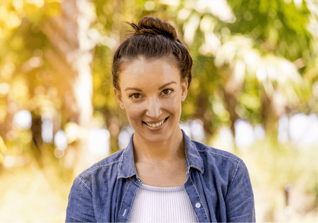 A woman smiling and standing in front of trees